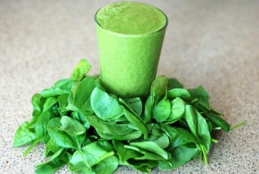 a green smoothie with spinach around the glass