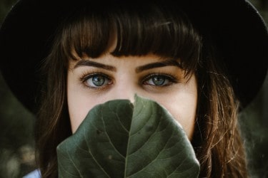 Woman covering her nose and mouth with a leaf