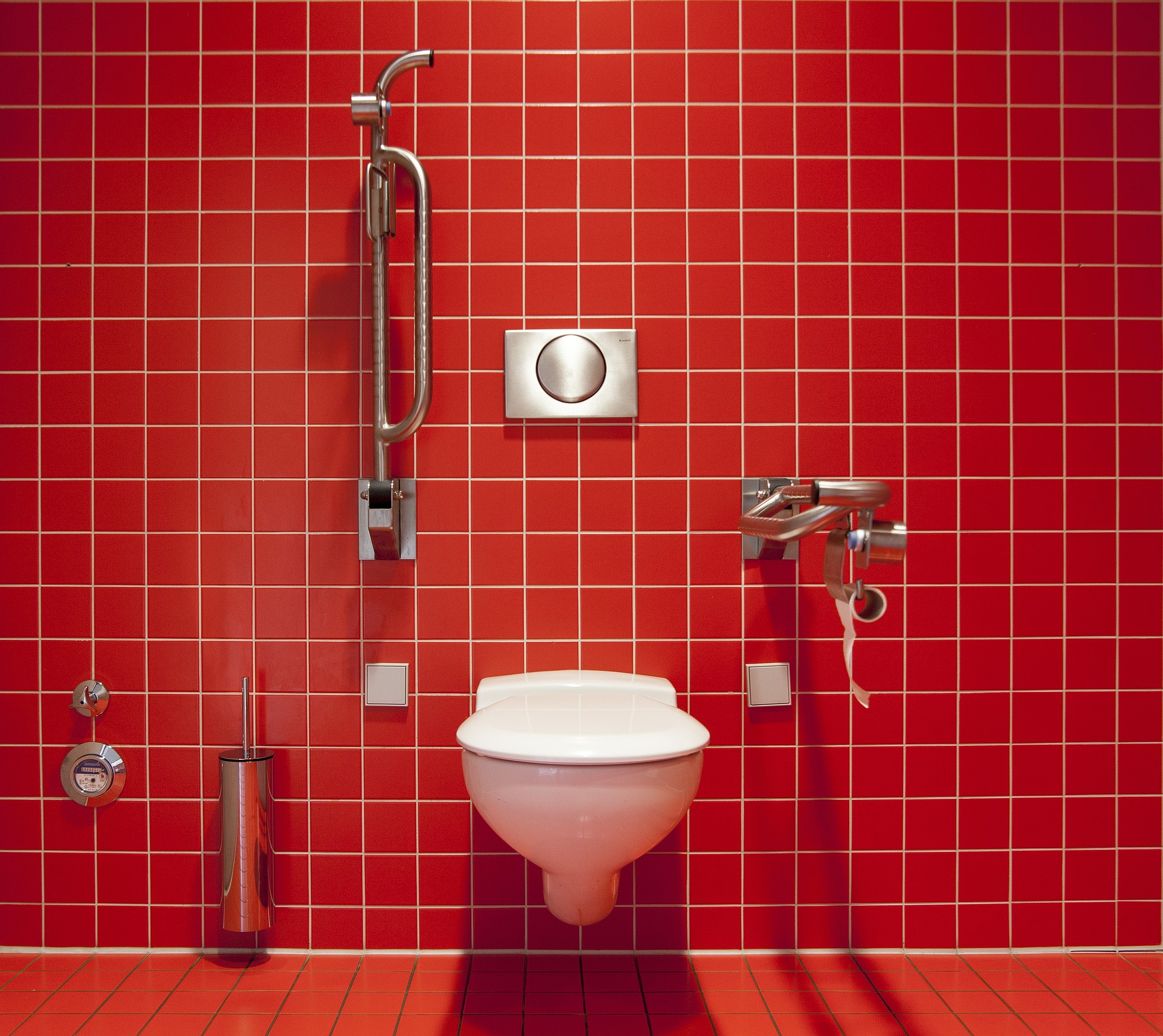 a toilet in a red tiled bathroom 