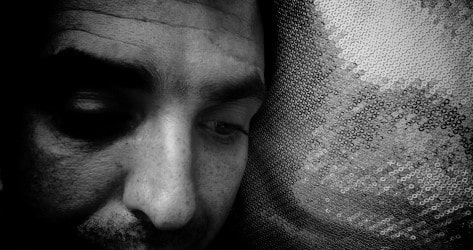 black and white photo of the upper half of a mans face against a pillow 