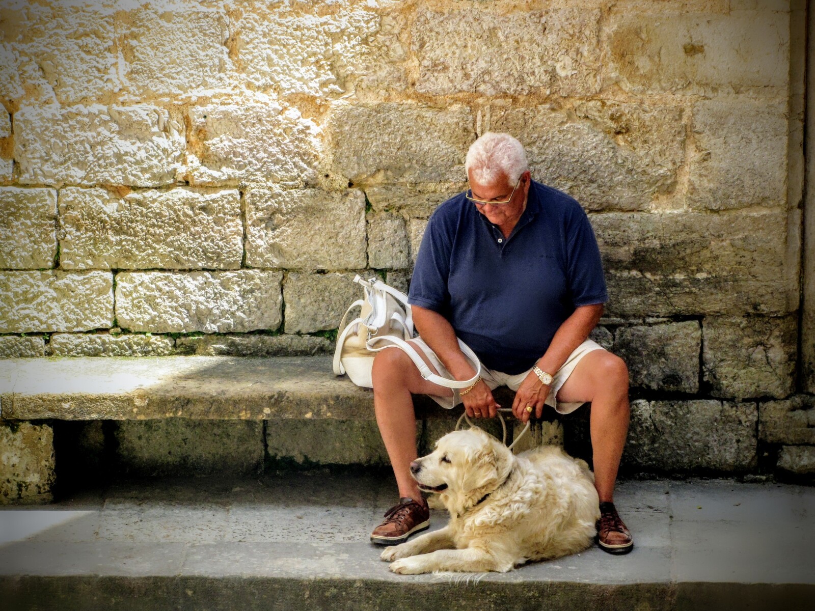 a man sitting down on a bench with his dog 