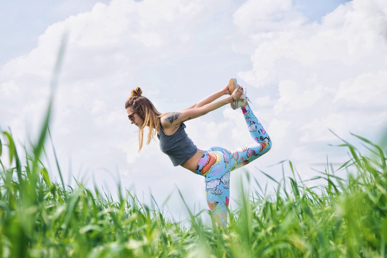 a woman doing yoga in a field of grasss