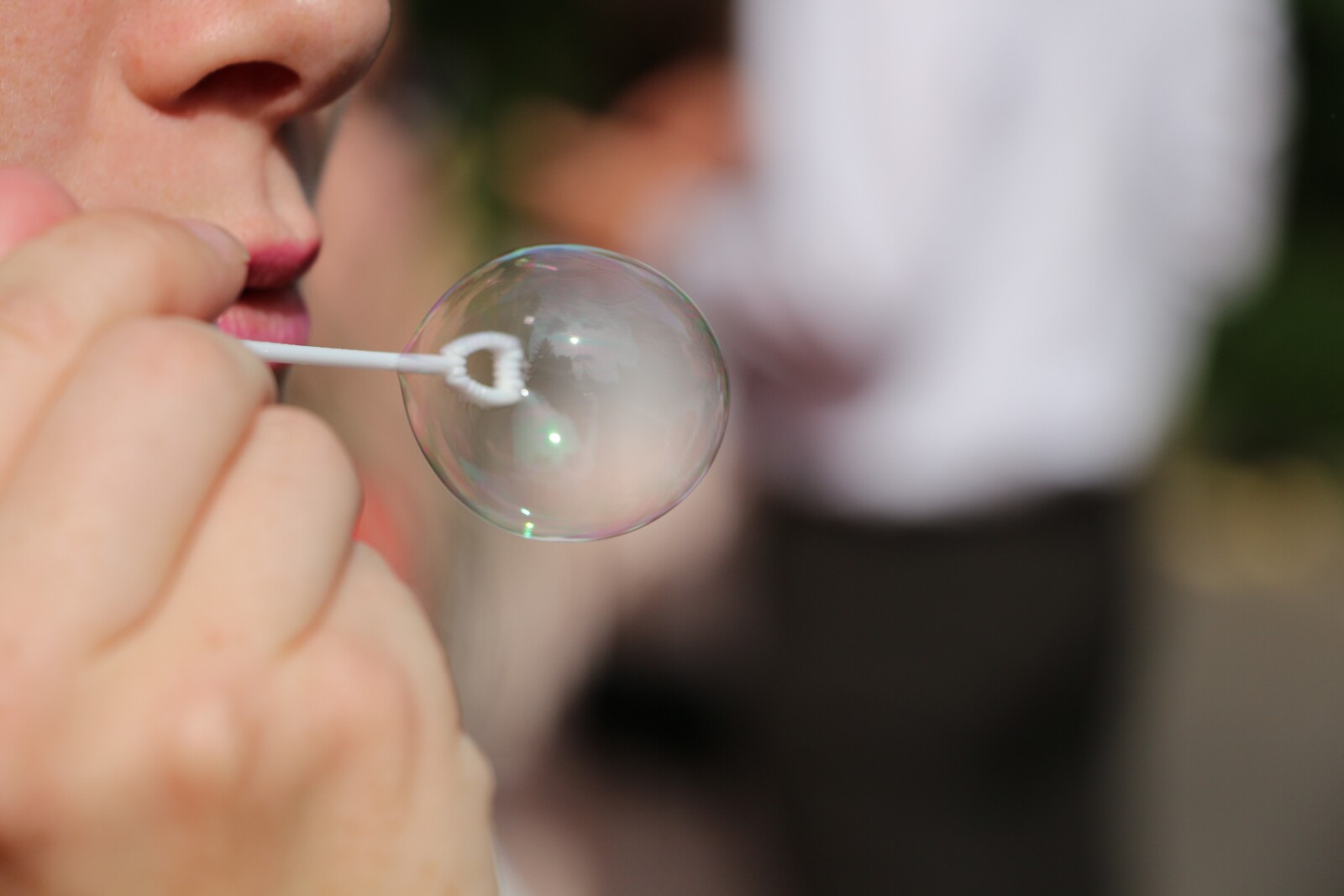 a person blowing a bubble from a bubble stick