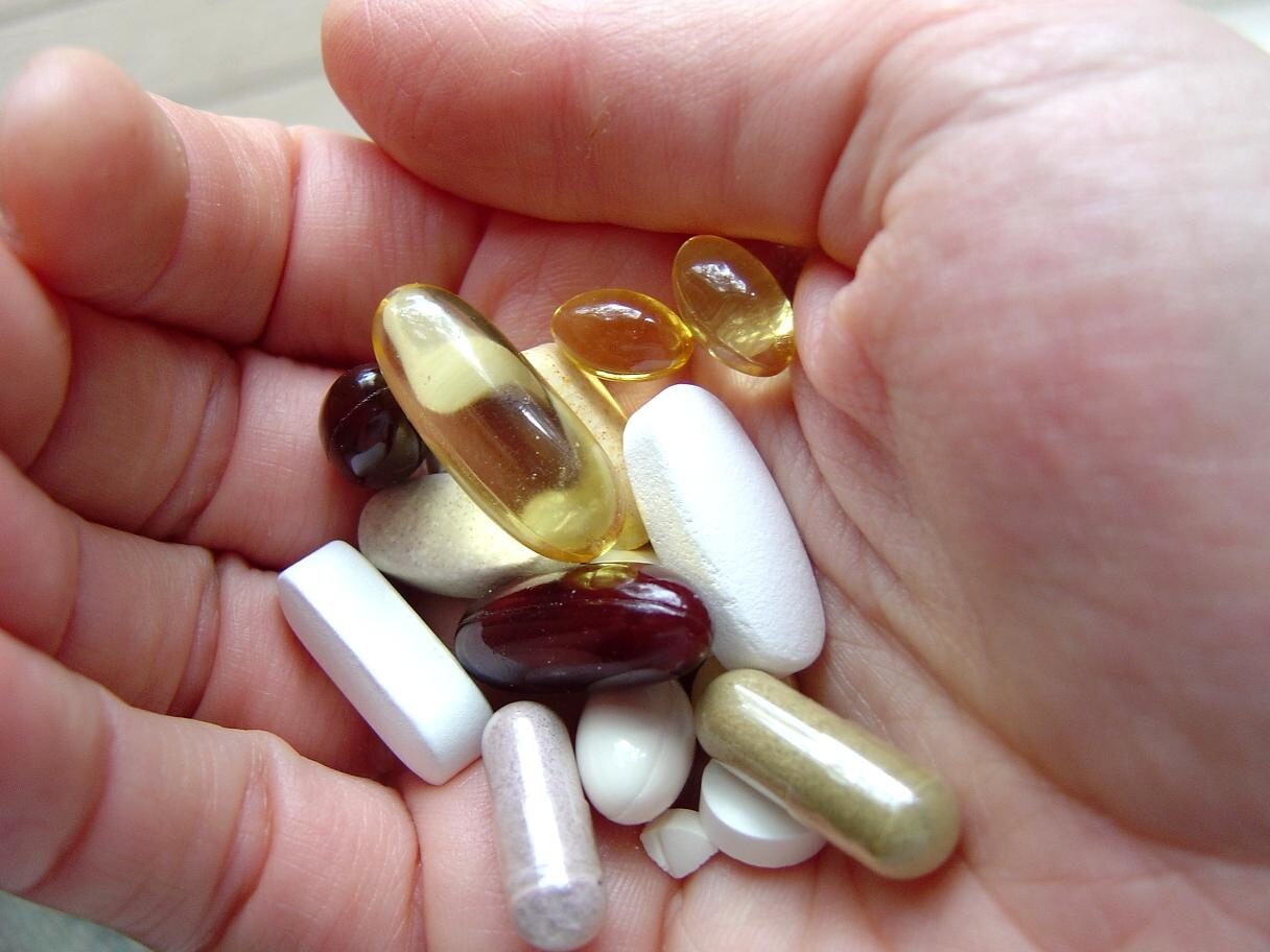 A person holding several vitamins in their hand