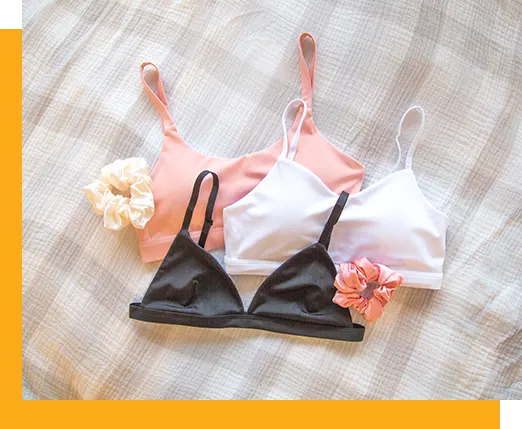 A photo of three sports bras on a bed with two hair scrunchies