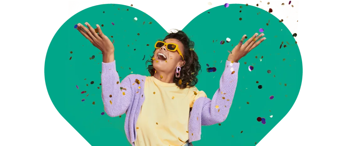 Femme souriante et lançant des confettis en l’air sur un fond en forme de cœur