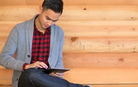man sitting on a bench using a tablet