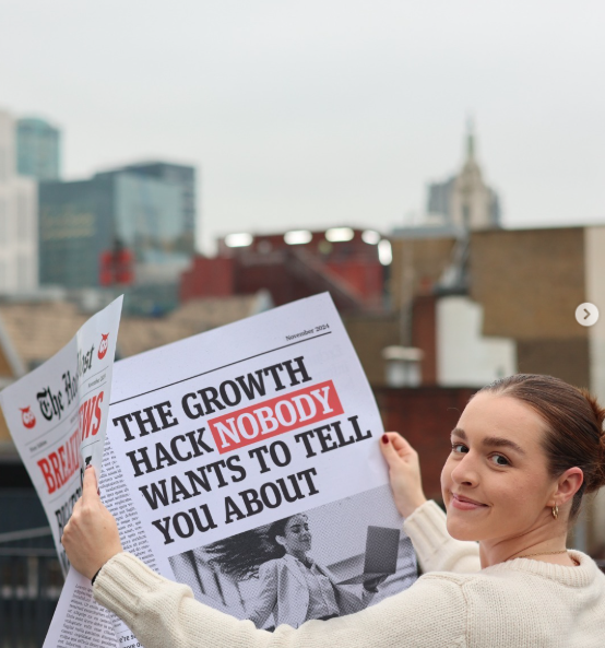 Woman holding huge newspaper that reads 'The growth hack nobody wants to tell you about'