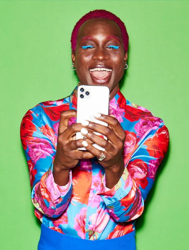 A headshot of a person with pink hair holding an iphone