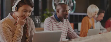 Students sitting at a table in a room with a laptop computer taking a training course