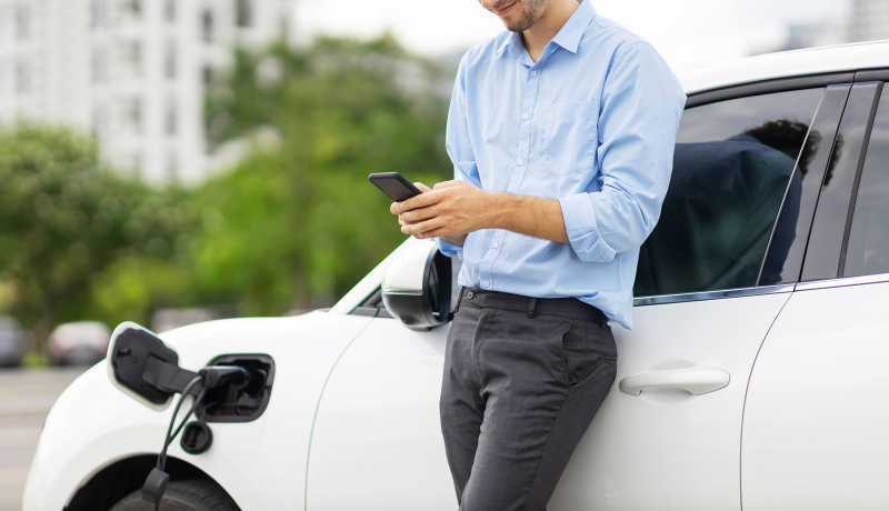 Mann vor Auto Phone gewerbliche Kfz-Versicherung