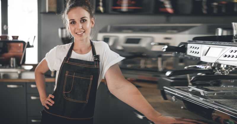 Cafe eröffnen: Frau mit Schürze im Cafe