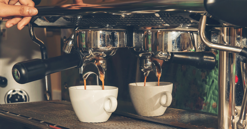 Eine weiße Kaffeetasse steht unter einer Espressomaschine