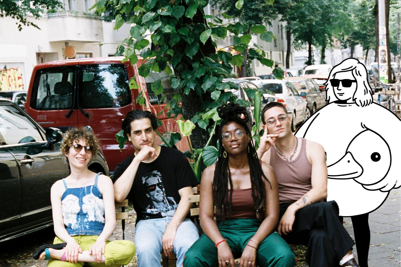 The four breakfast show hosts sit on  weserstraße alongside a minor figures cartoon character.