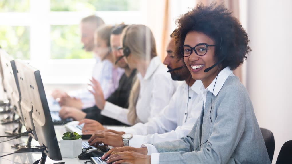 Woman in call center wearing headset smiles into camera
