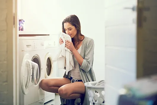 Woman Enjoying The Fresh Scent Of Laundry In A Laundry Room
