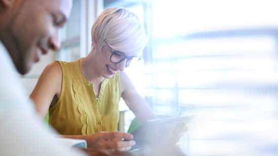 Image of two employees doing intelligent pulse surveys on a tablet