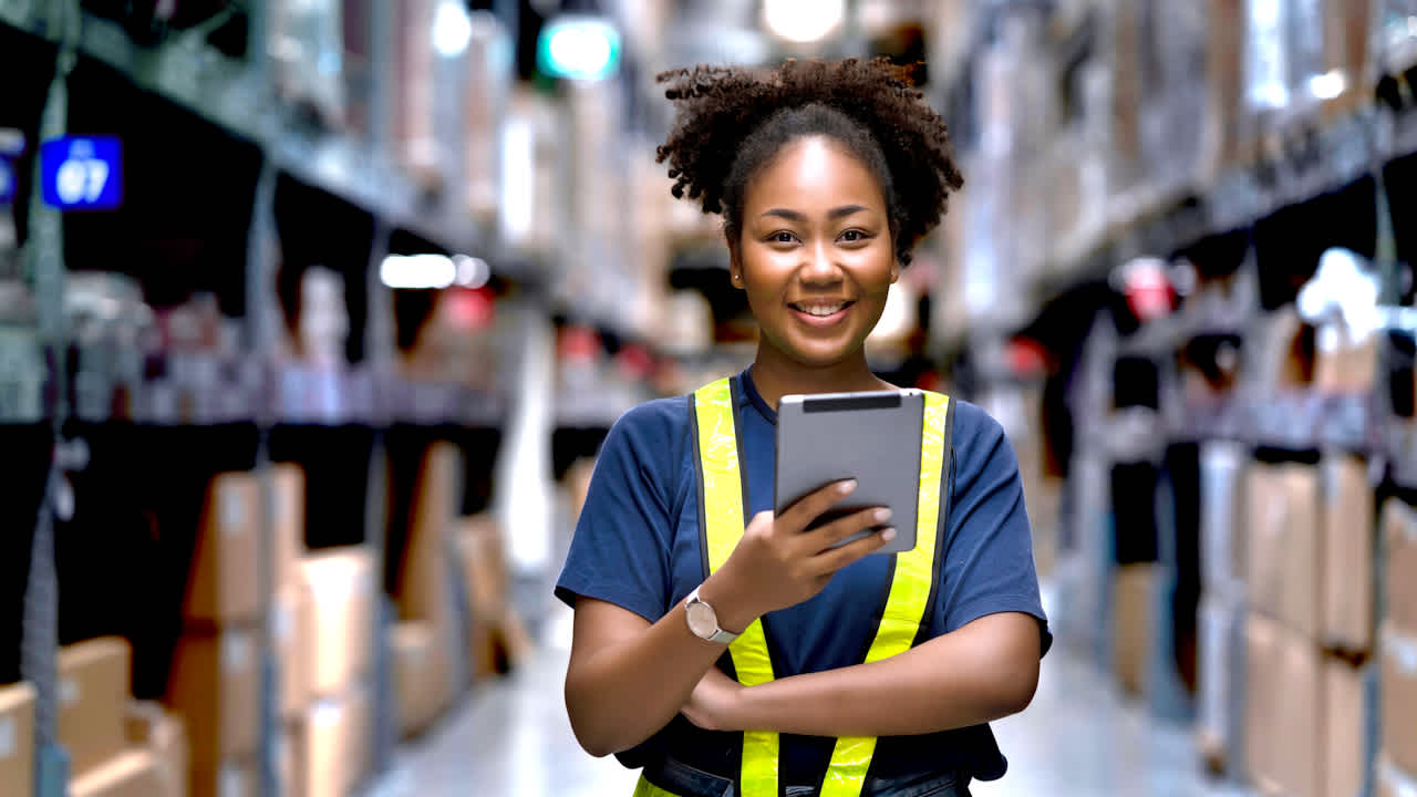 Image of a happy warehouse worker with a tablet in her hand