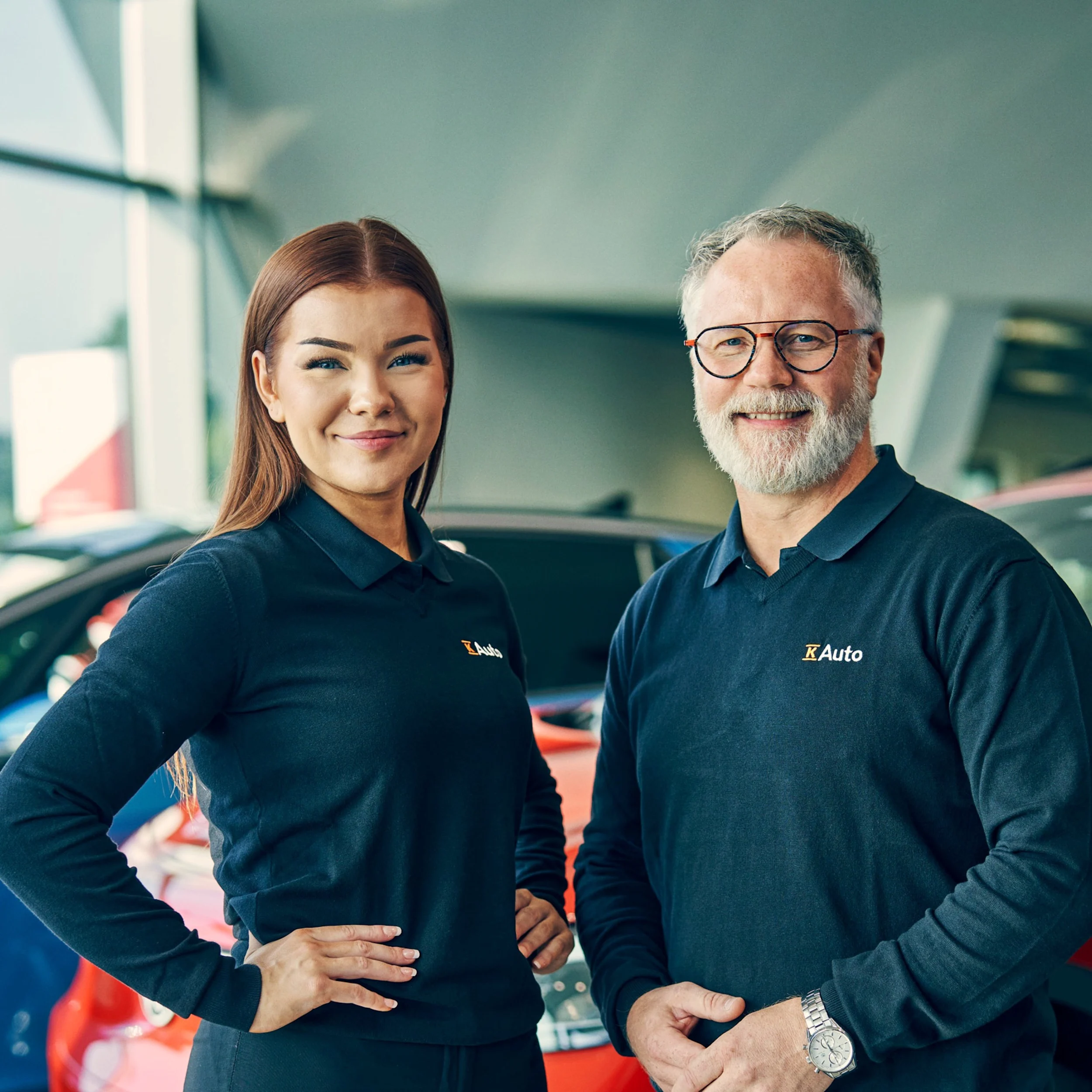 K-Auton kaksi automyyjää sekä autovalikoima heidän takana