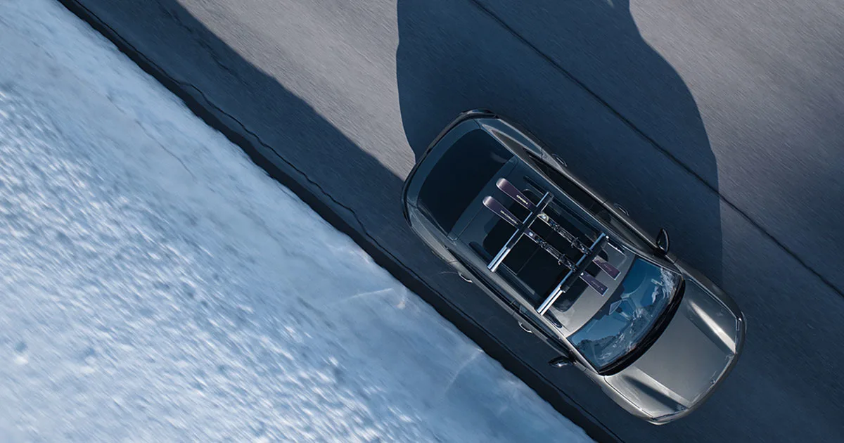 Porsche Macan sukset katolla ajaa lumista tietä.