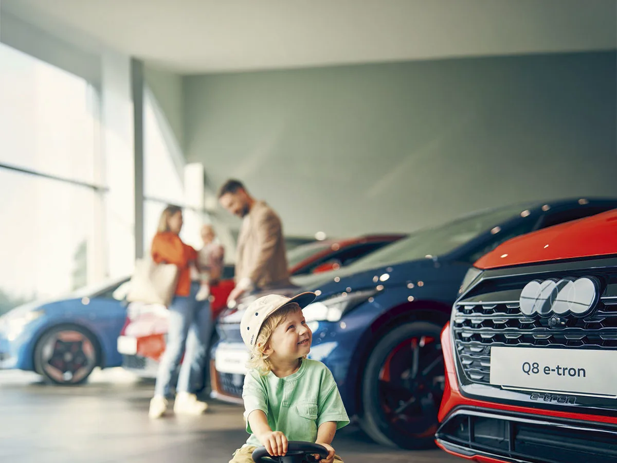 Perhe tutkii uusien autojen valikoimaa myymälässä.