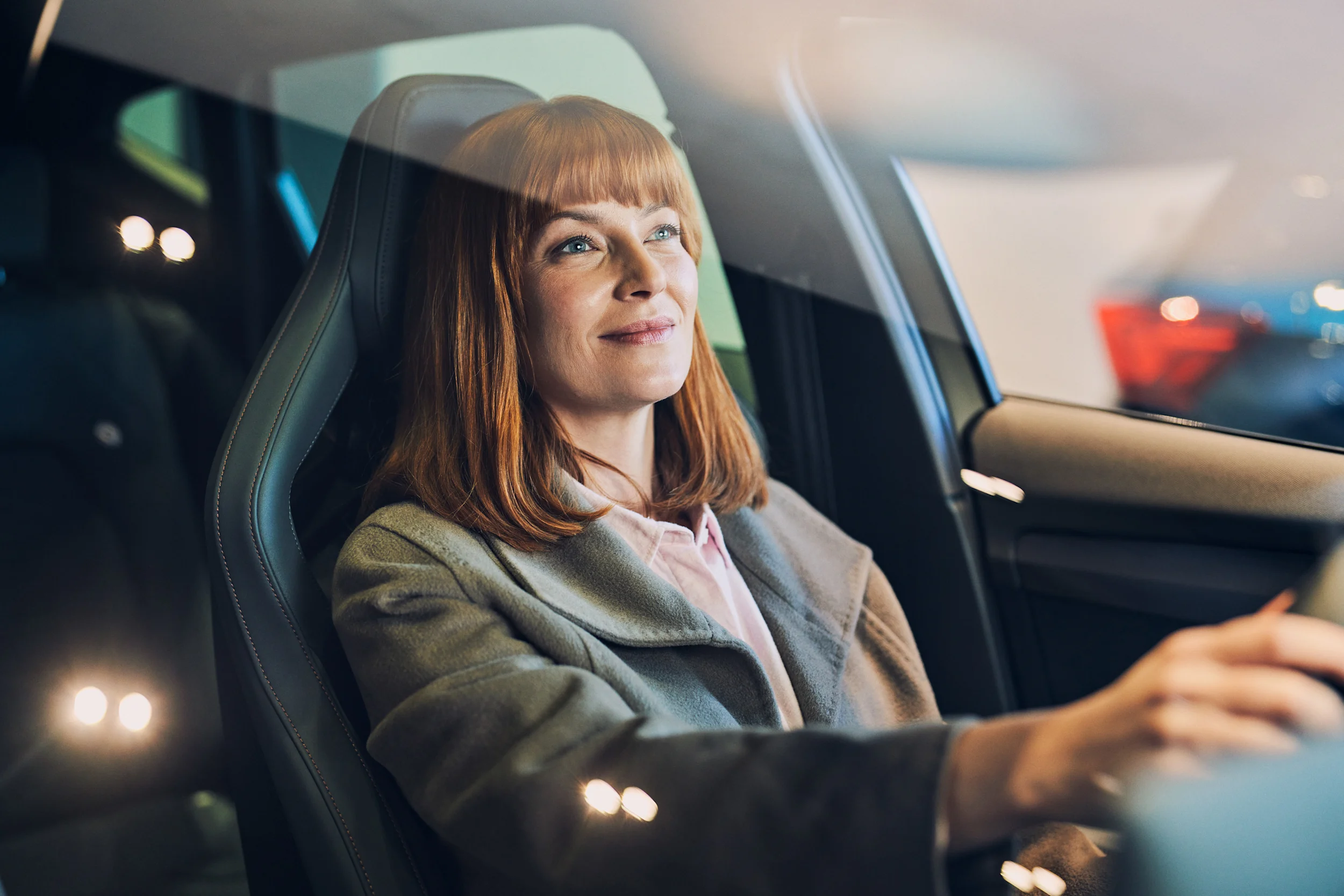 Hymyilevä nainen istuu autossa.