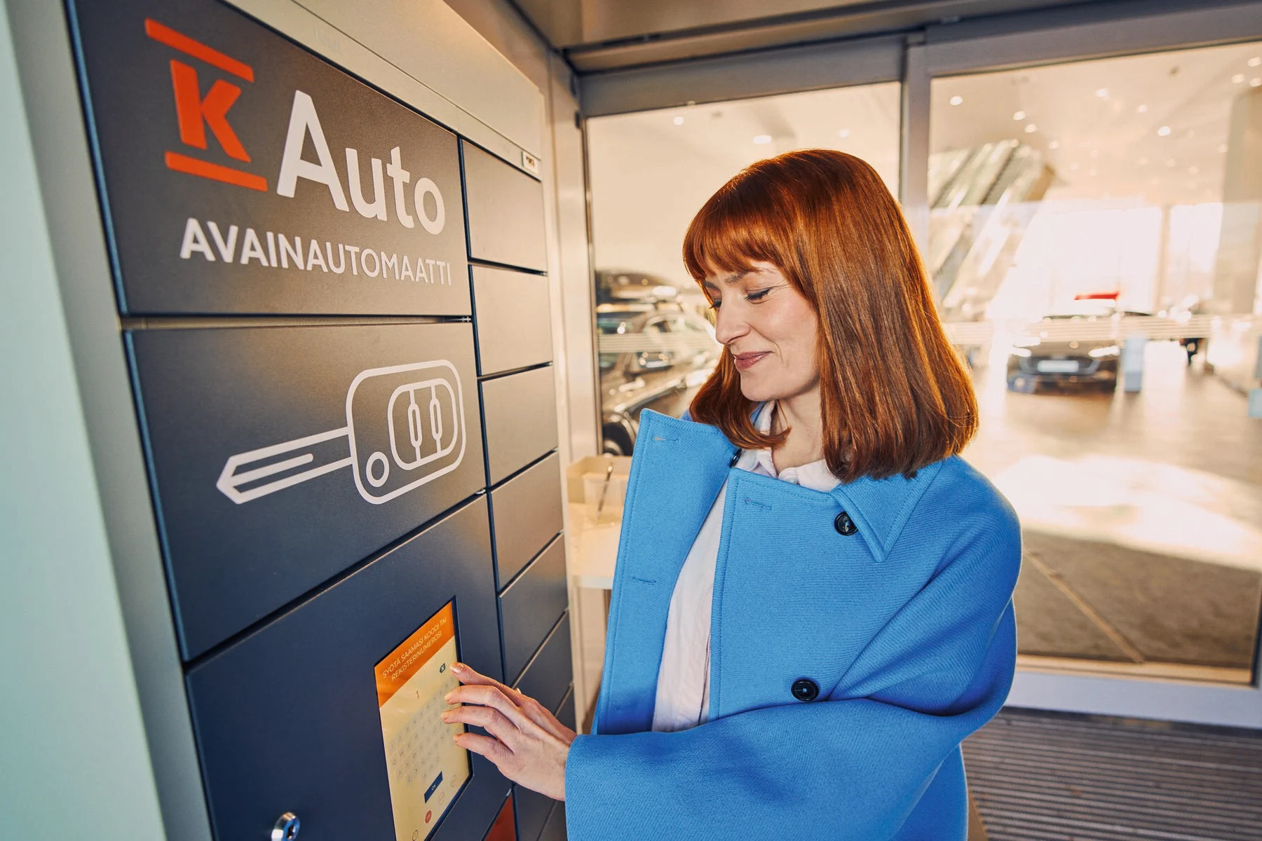 Nainen hakee avaimen K-Auton avainautomaatista.