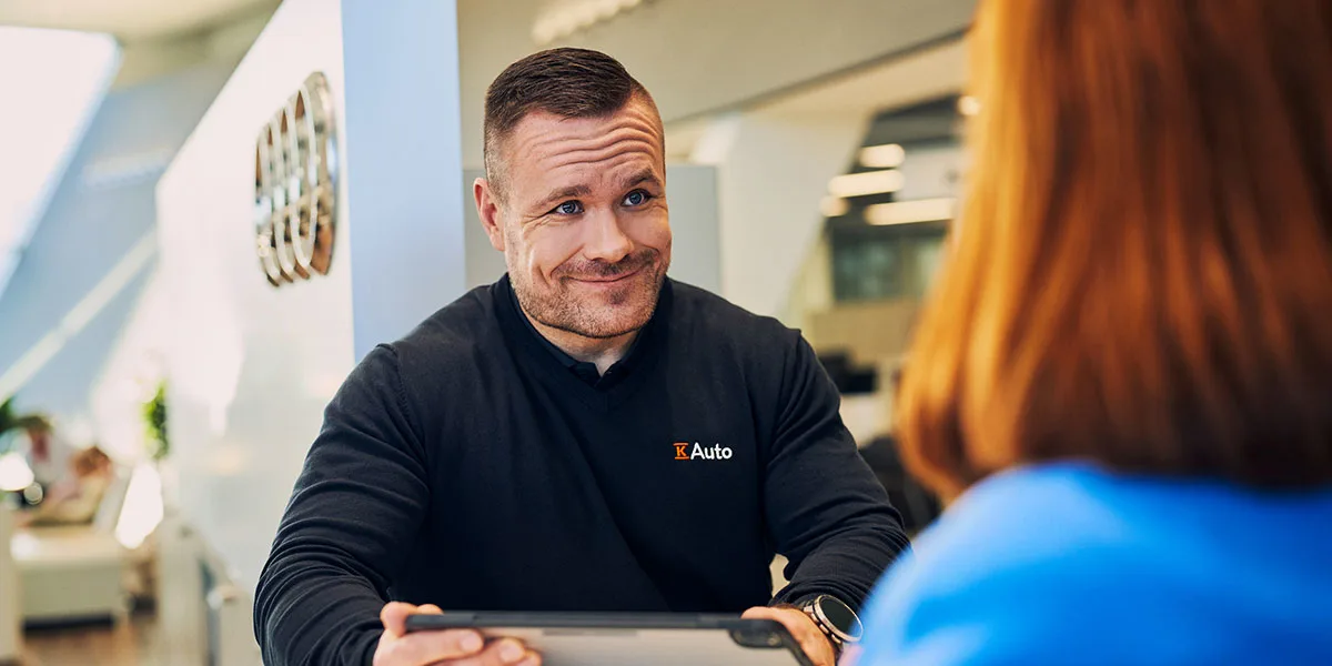 K-Auton automyyjä neuvoo asiakasta palvelutiskillä.