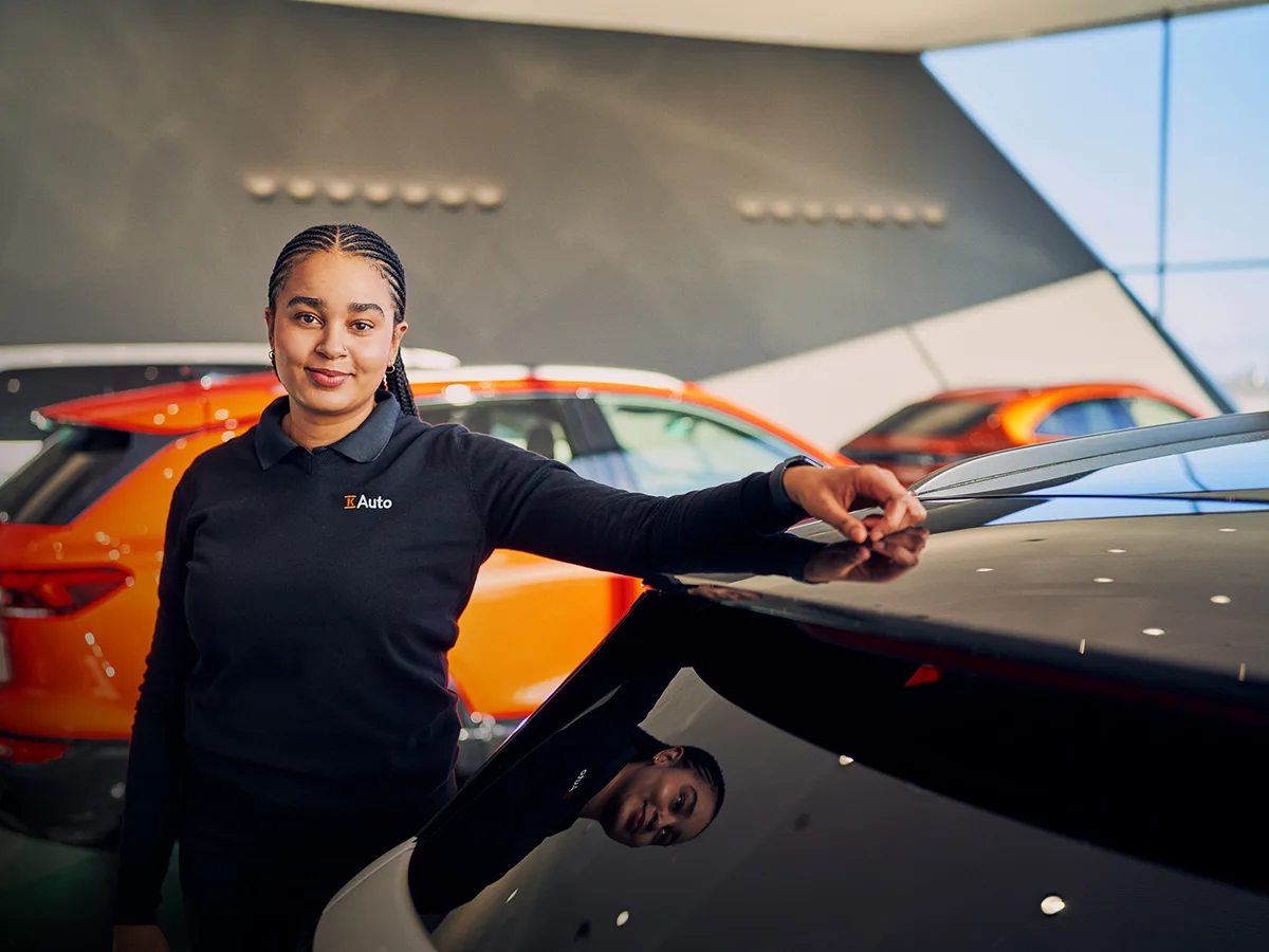 Hymyilevä K-Auton työntekijä nojaa esittelyautoon