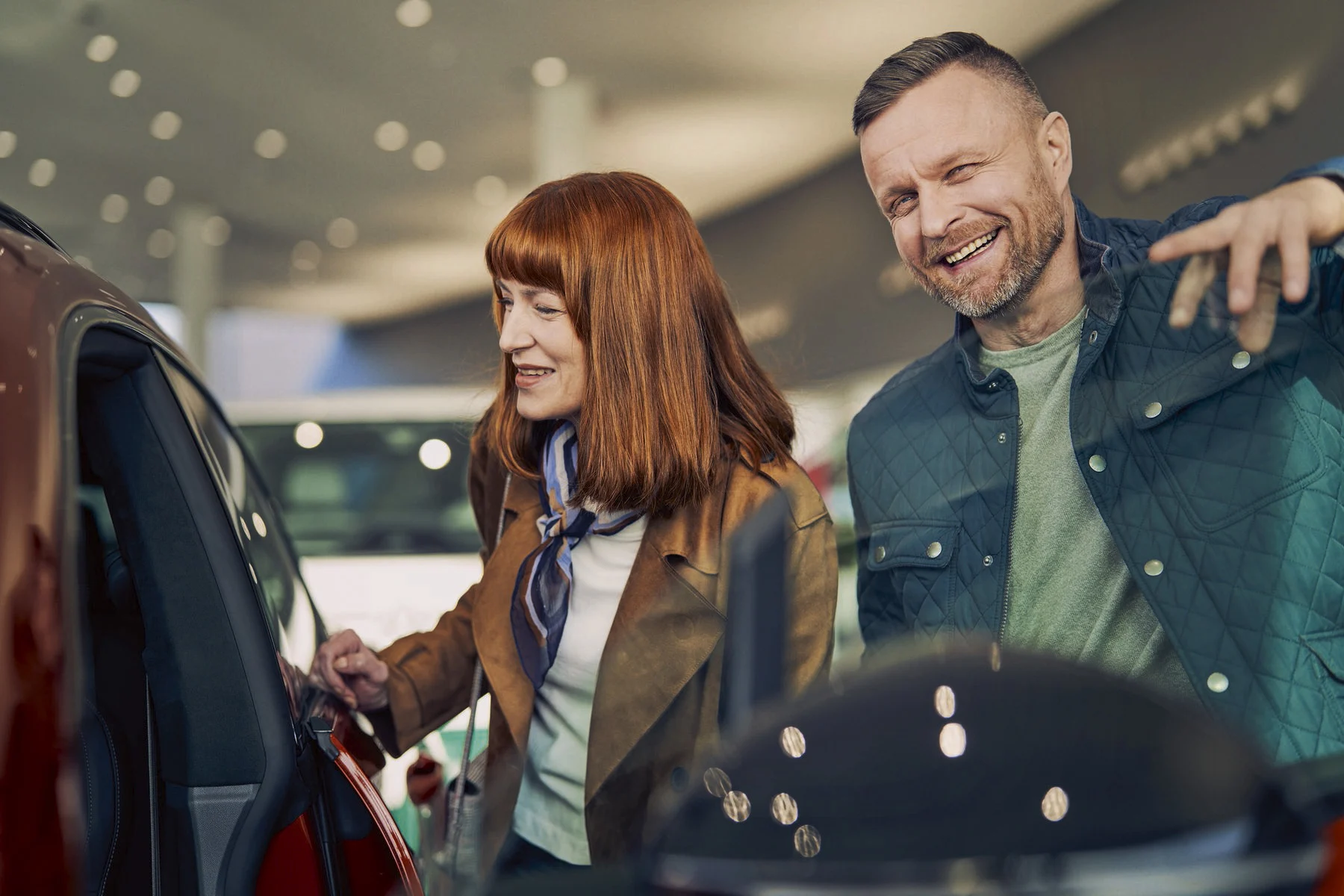 Nainen ja mies tutkivat autoa myymälässä.