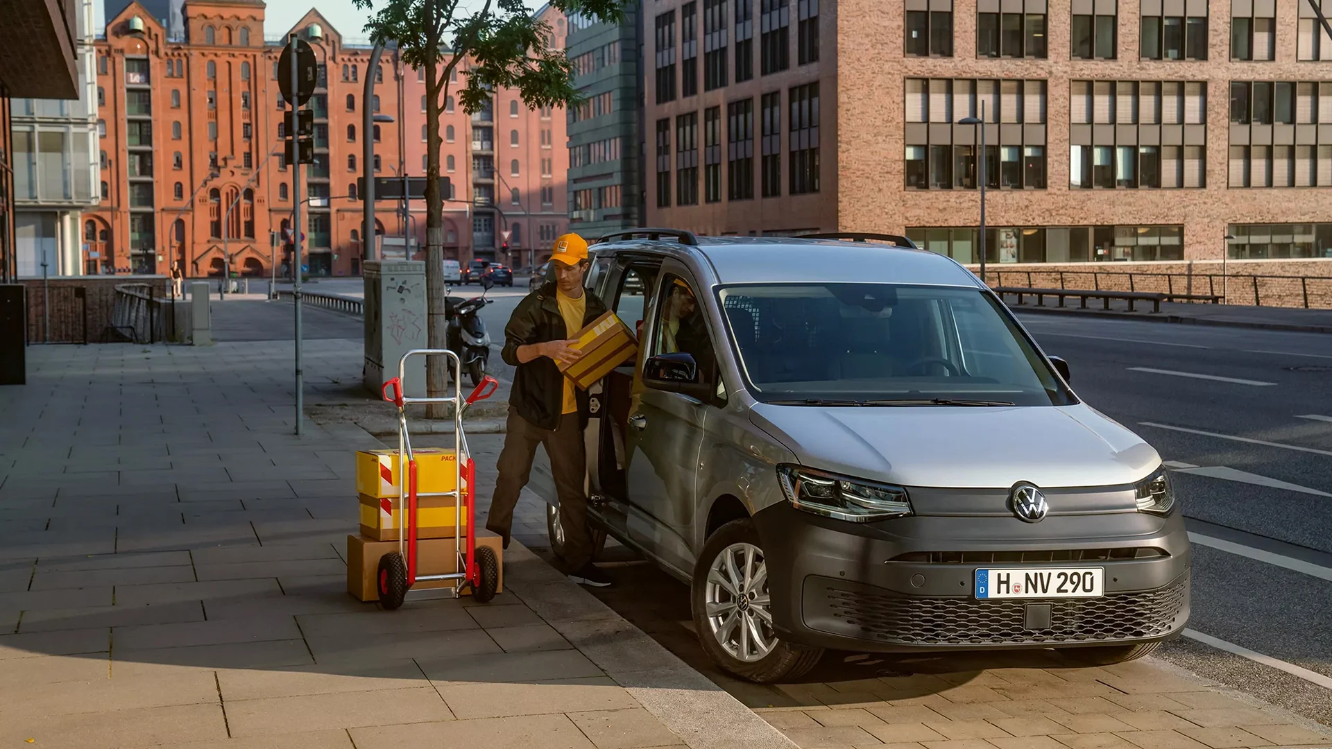 Henkilö lastaa Volkswagen Caddy Maxi pakettiautoa sivuovesta.