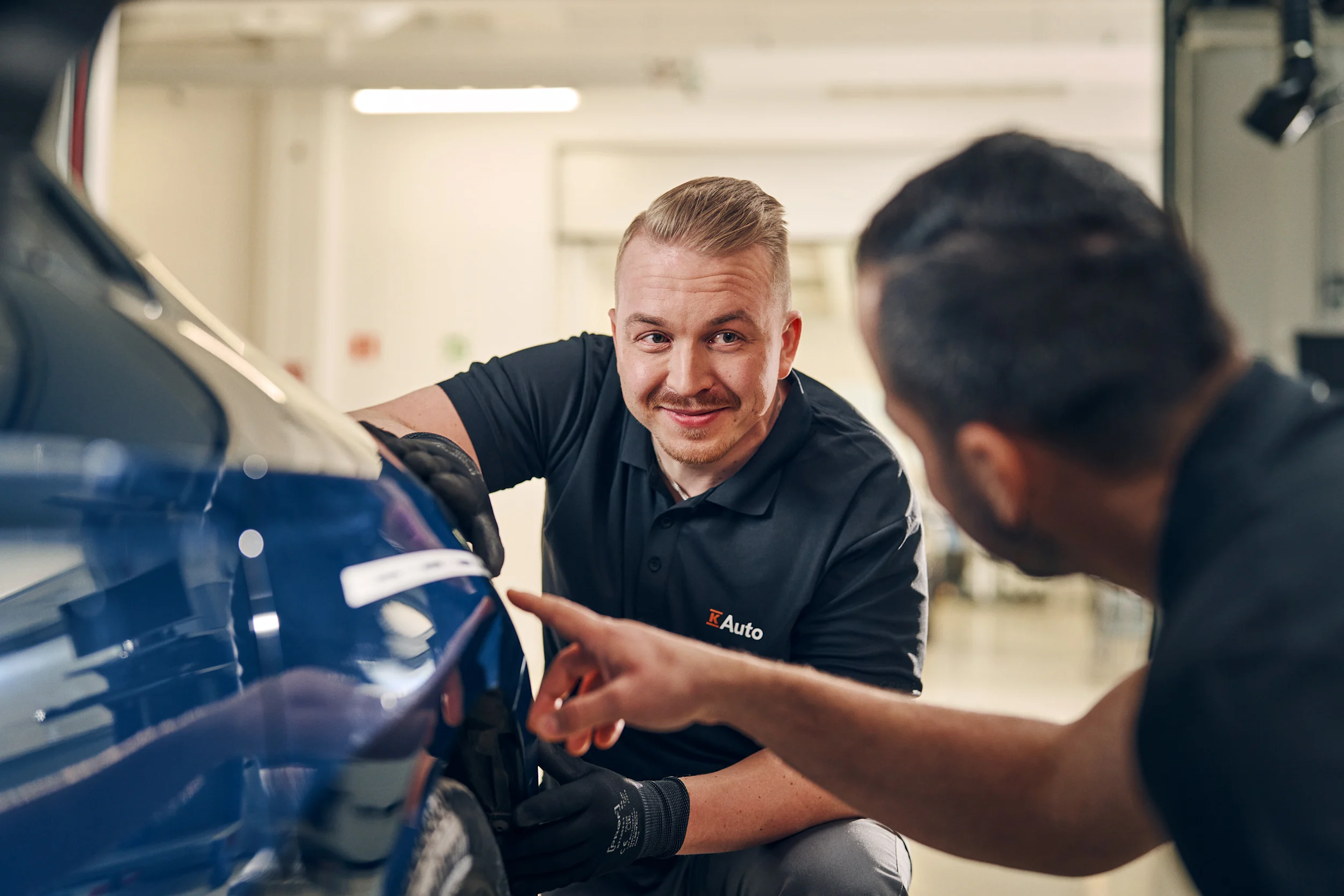Huoltohenkilökunta korjaa auton keulaa.