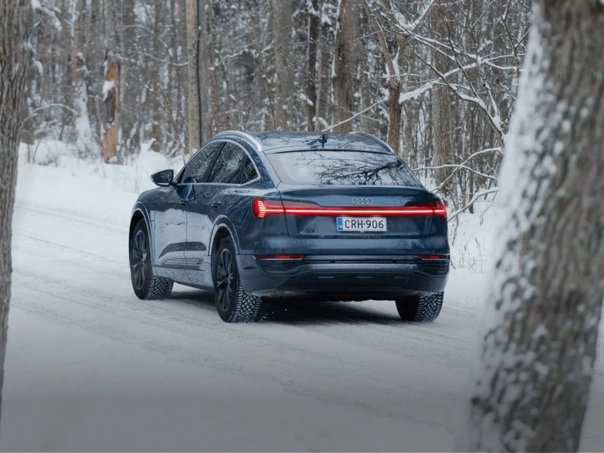 Sininen Audi Q8 Sportback e-tron ajamassa lumisella tiellä talvirenkaat alla