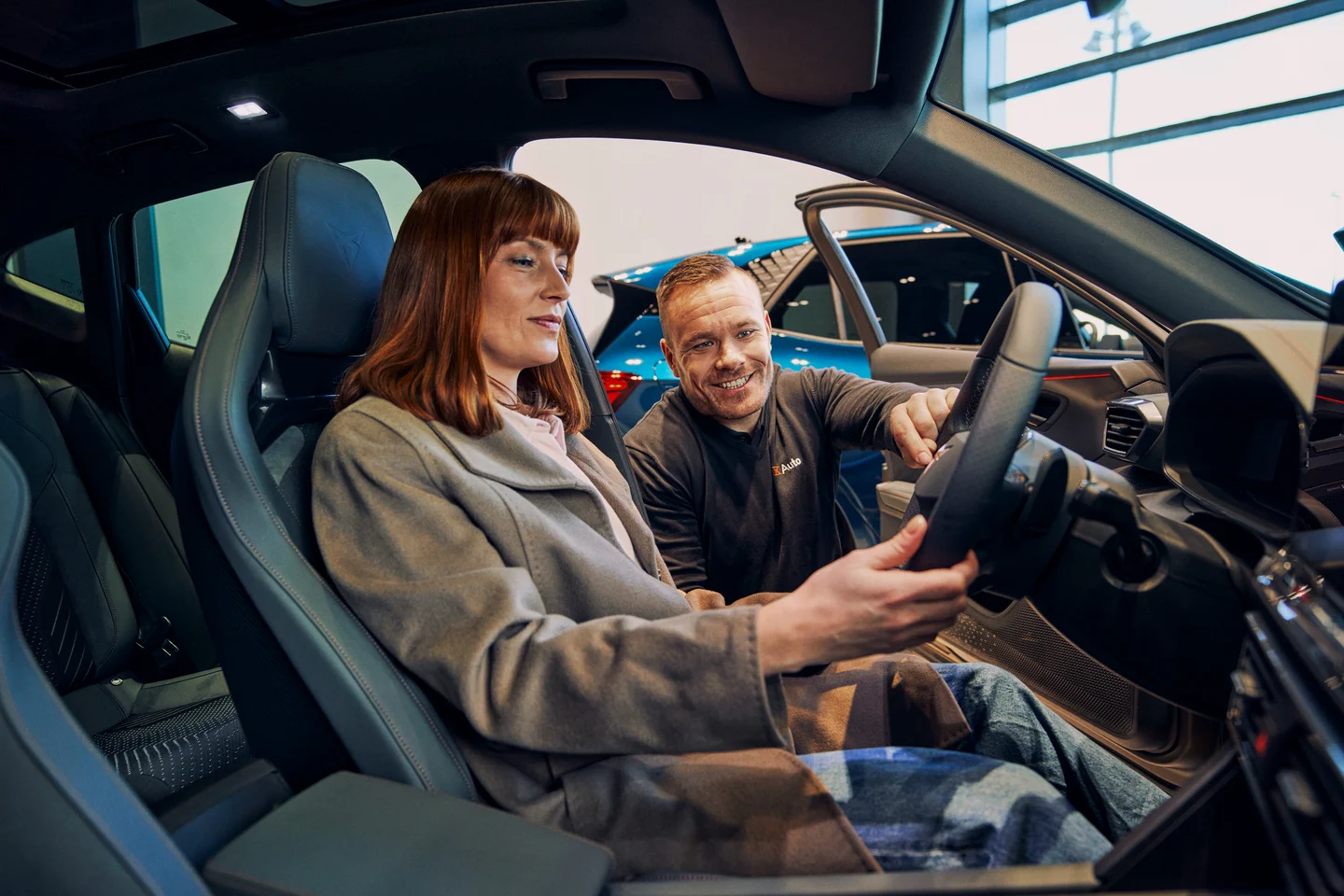 Leasing auton valinta - myyjä auttaa autossa istuvaa naista leasing-auton kanssa