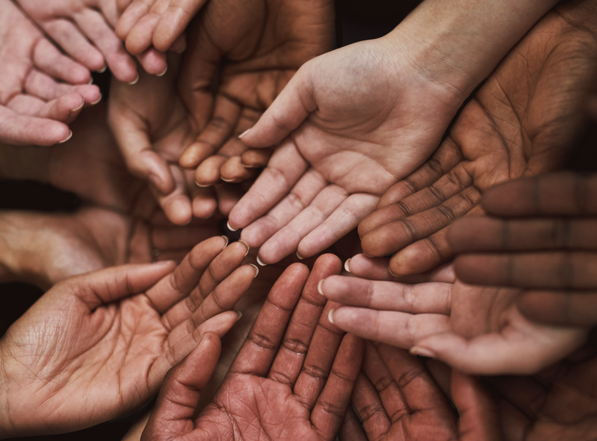 Multiple hands joined in the center waiting to receive something.