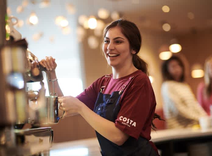 Costa Coffee Barista Frau an Siebträgermaschine