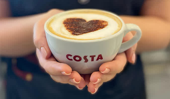 Barista holding a Costa Coffee cup