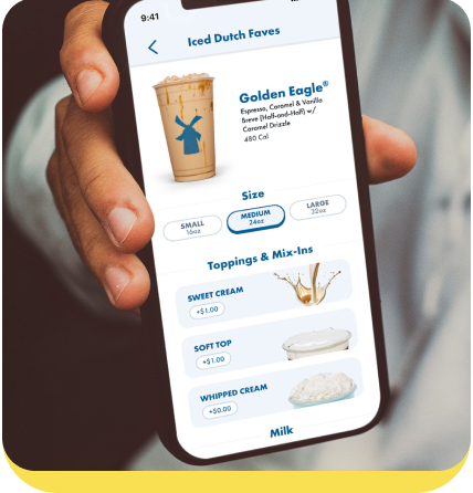 Hand holding phone displaying Dutch Bros coffee app with Golden Eagle drink options and topping selections