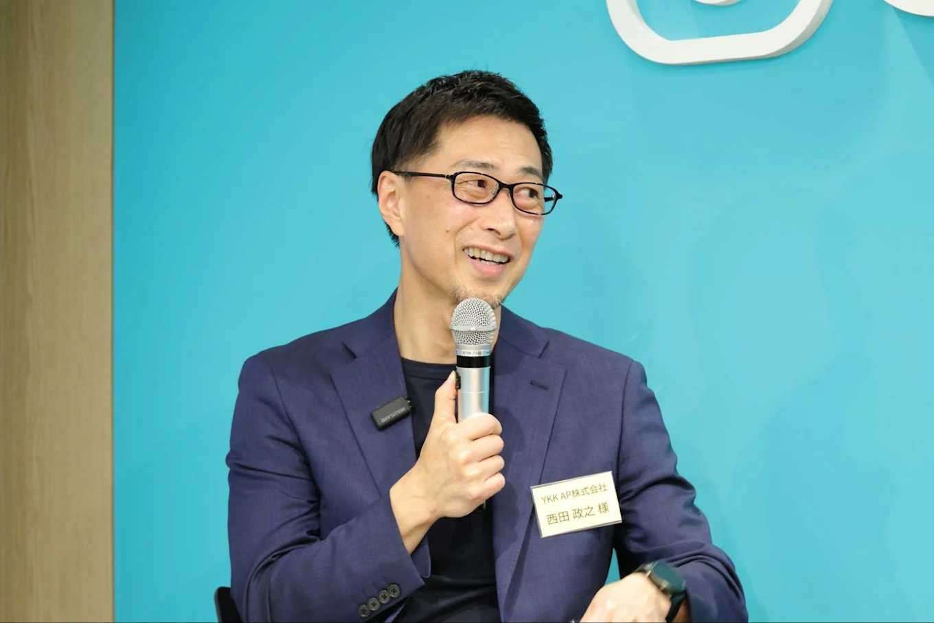 マイクを持ちながら笑顔で話す西田さんの写真