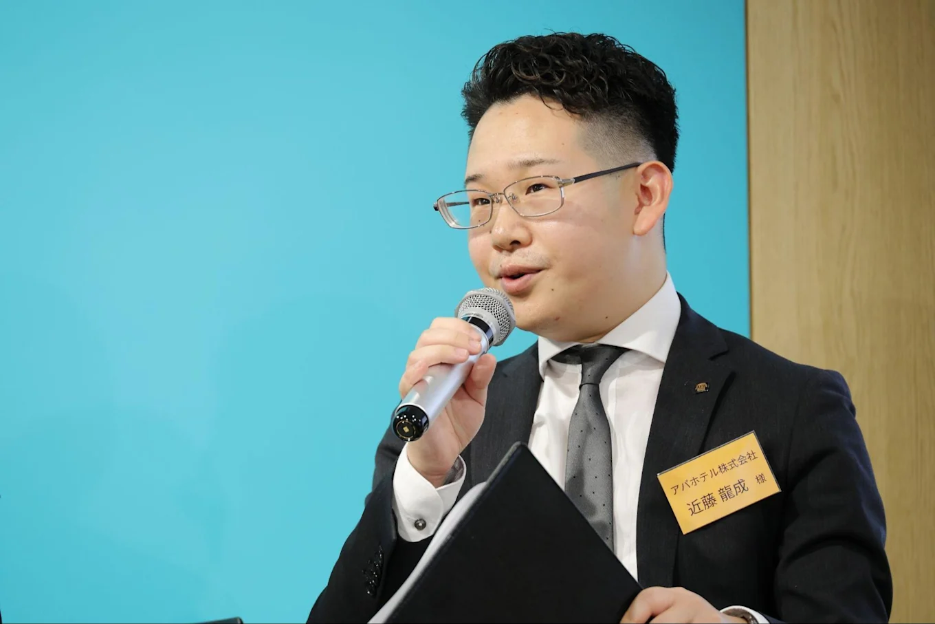 マイクとバインダーを持ちお話しされている近藤さん