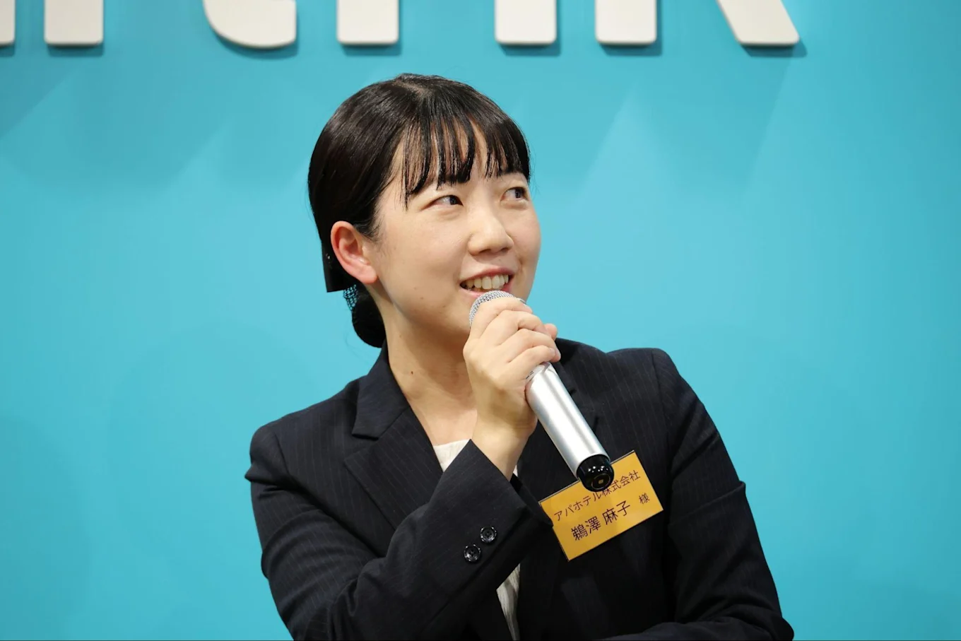 マイクを片手にお話しされる鵜澤さん。左を向いている