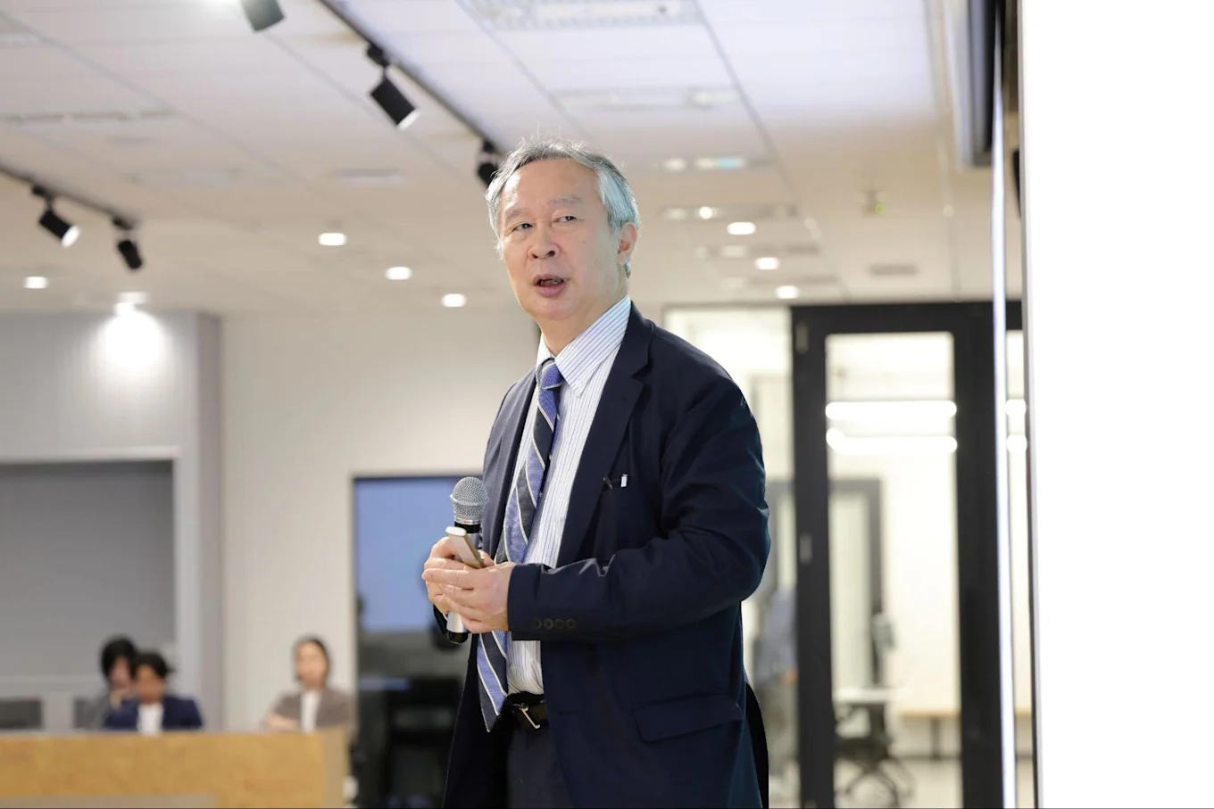 マイクを手に投影資料に目をやりながら話す有沢さん