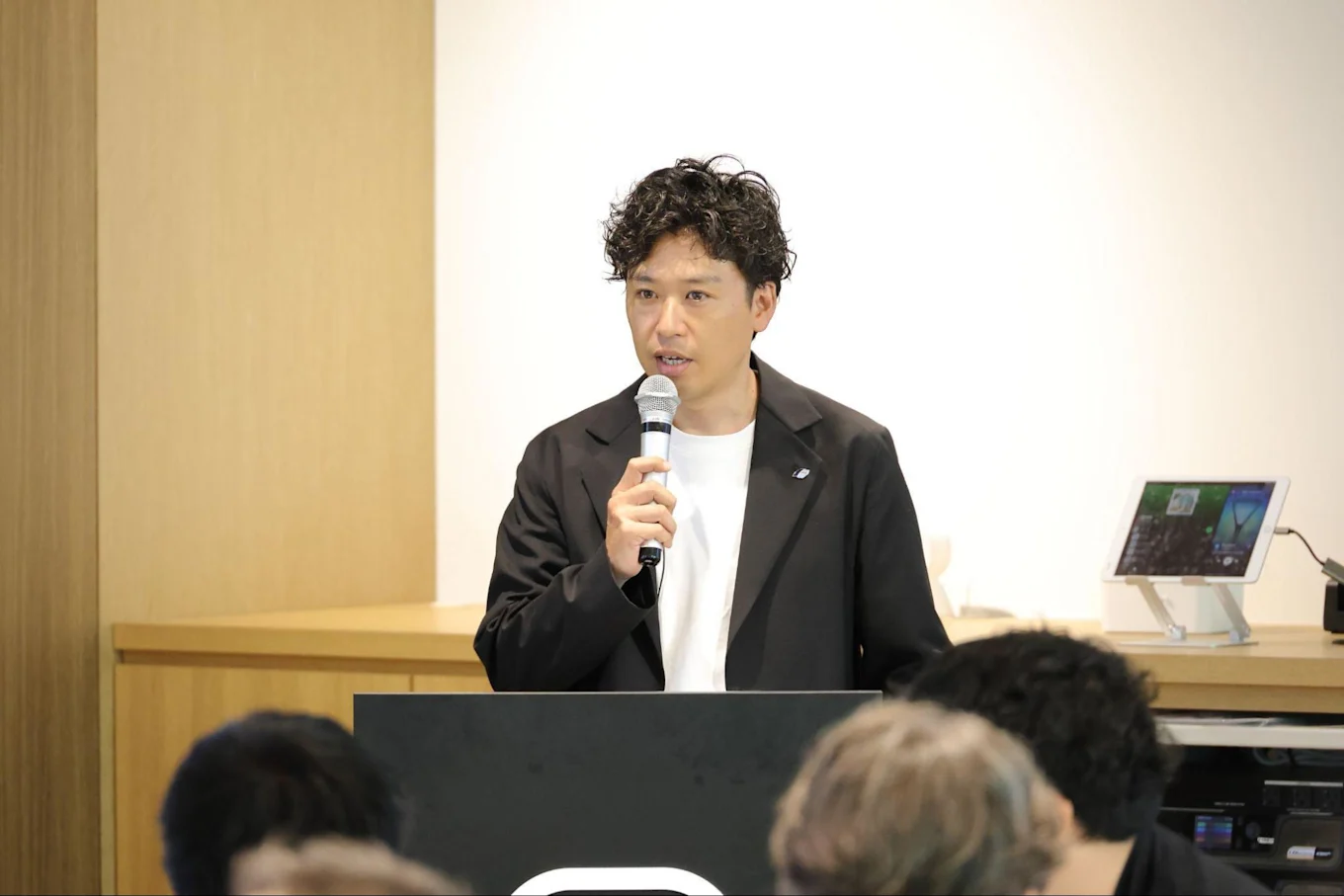 右手にマイクを持って話す須藤さん