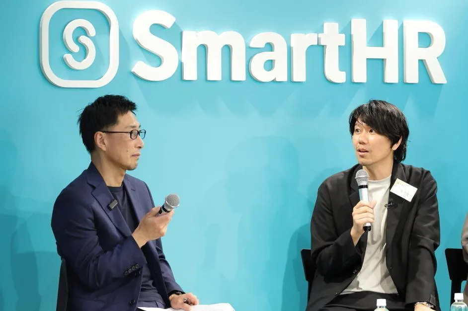 お互いに視線を合わせながらマイクを持って話す加藤さんを黙って聞いている西田さんの写真