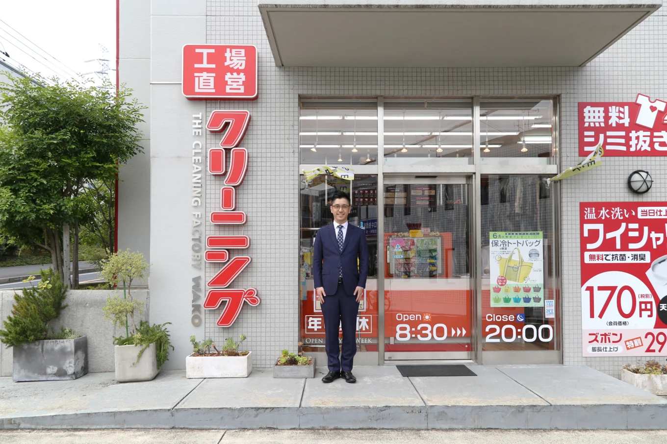 クリーニング店の前に立つ勝川さん