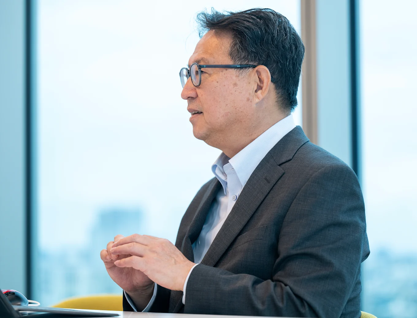 机にPCをに広げイスに座ってインタビューを受ける岩本さん