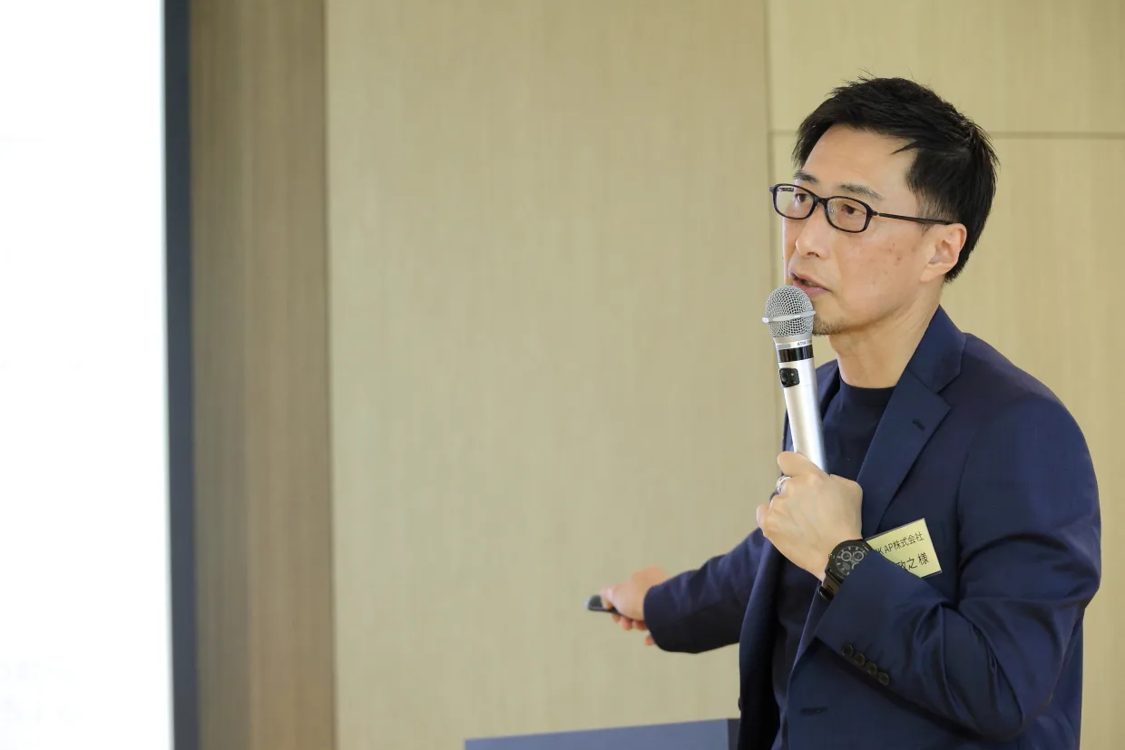 マイクを左手に、右手にレーザーポインタを持ち話をしている西田さん