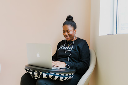 A woman typing on her laptop, wearing a Juno sweater