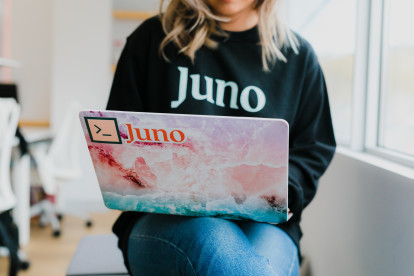 Women sitting with a laptop and wearing a black Juno sweater