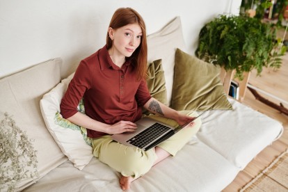 A woman sitting on a couch with her laptop